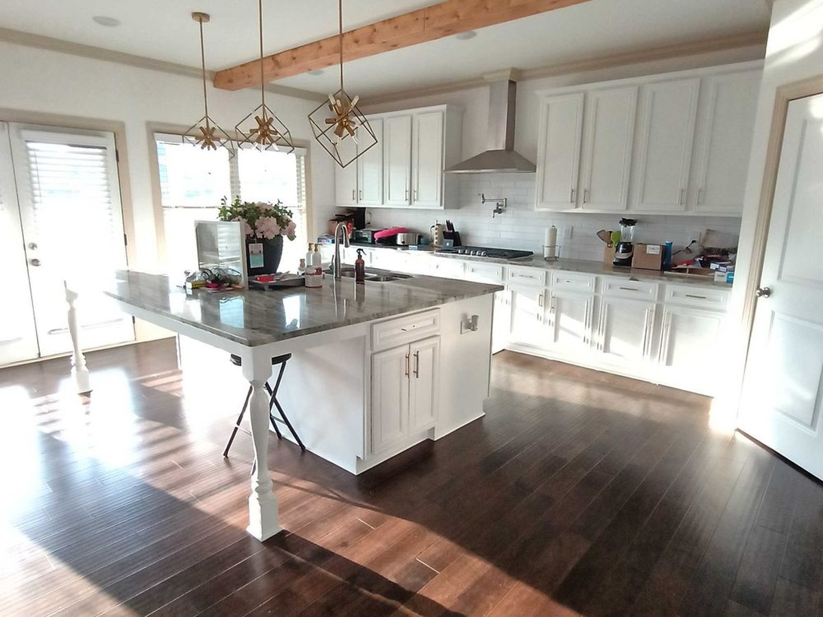An open kitchen with island and hardwood floors, cleaned and reset.