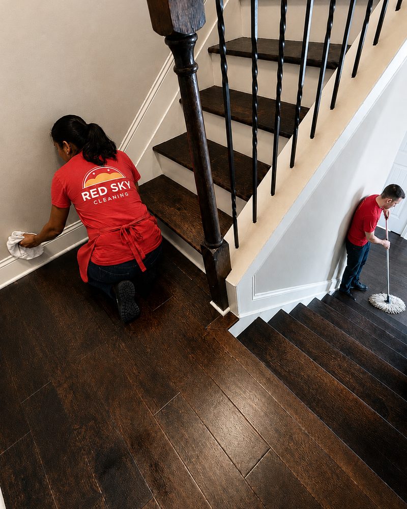 Red Sky cleaner hand-wiping baseboards and stairs on a move-out clean
